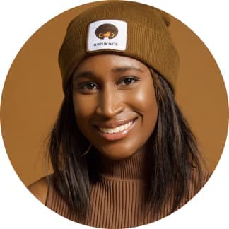CherRaye Glenn-Flowers of Brownce smiling and wearing a matching brown sweater and Brownce beanie.