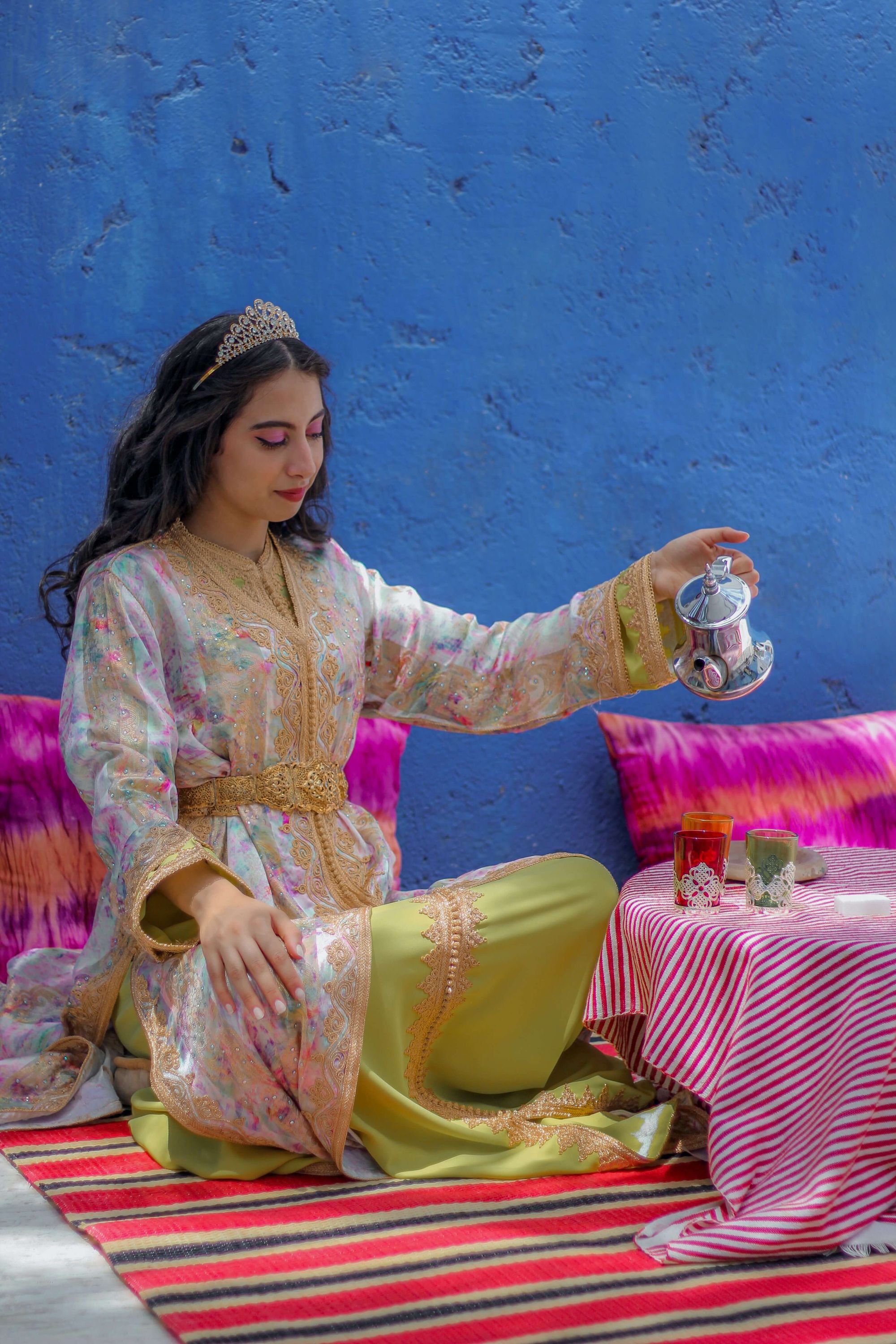 A women pouring tea, wearing a Moroccan Kaftan