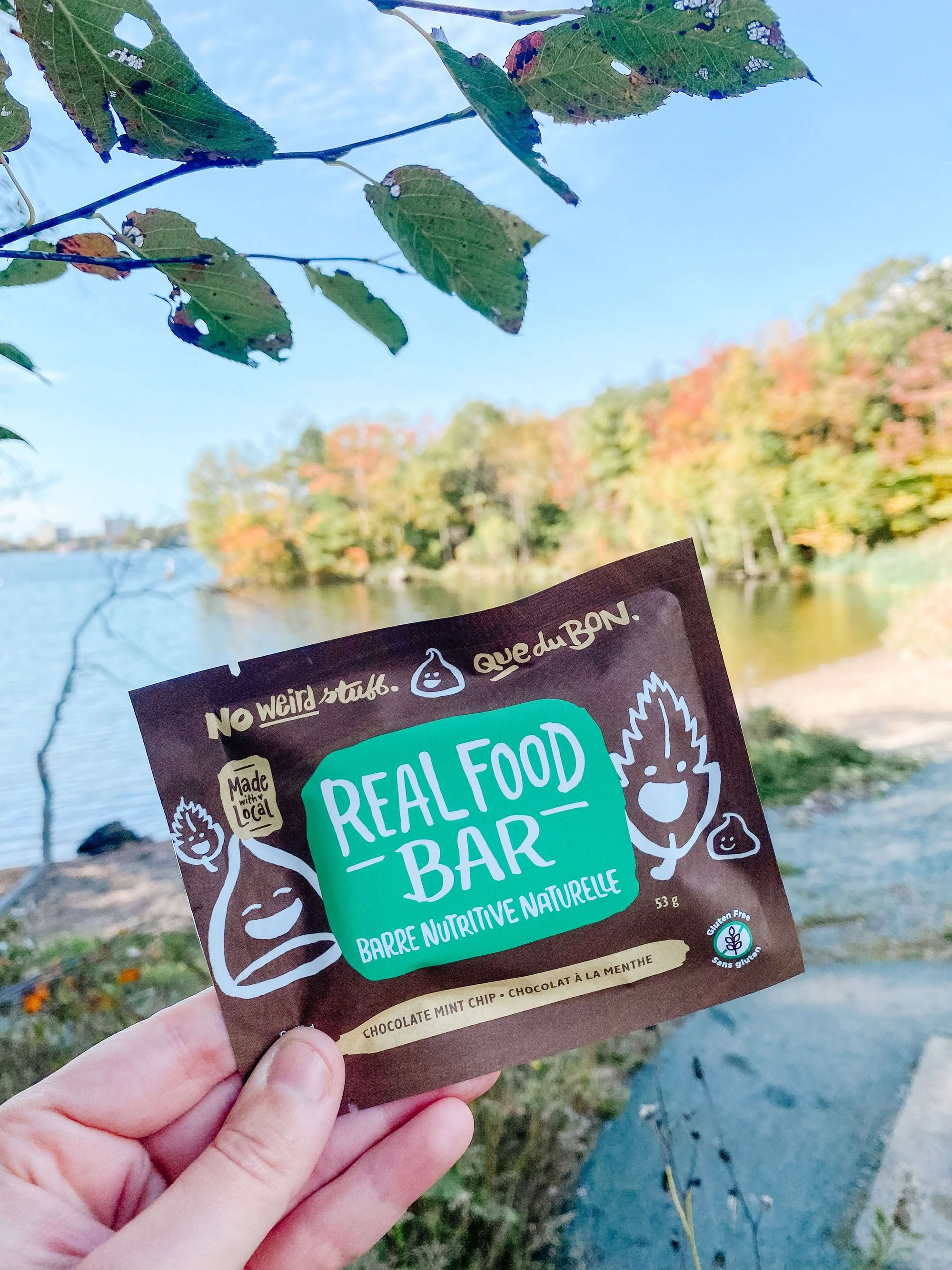 an image of person holding up a Made with Local granola bar in front of a river