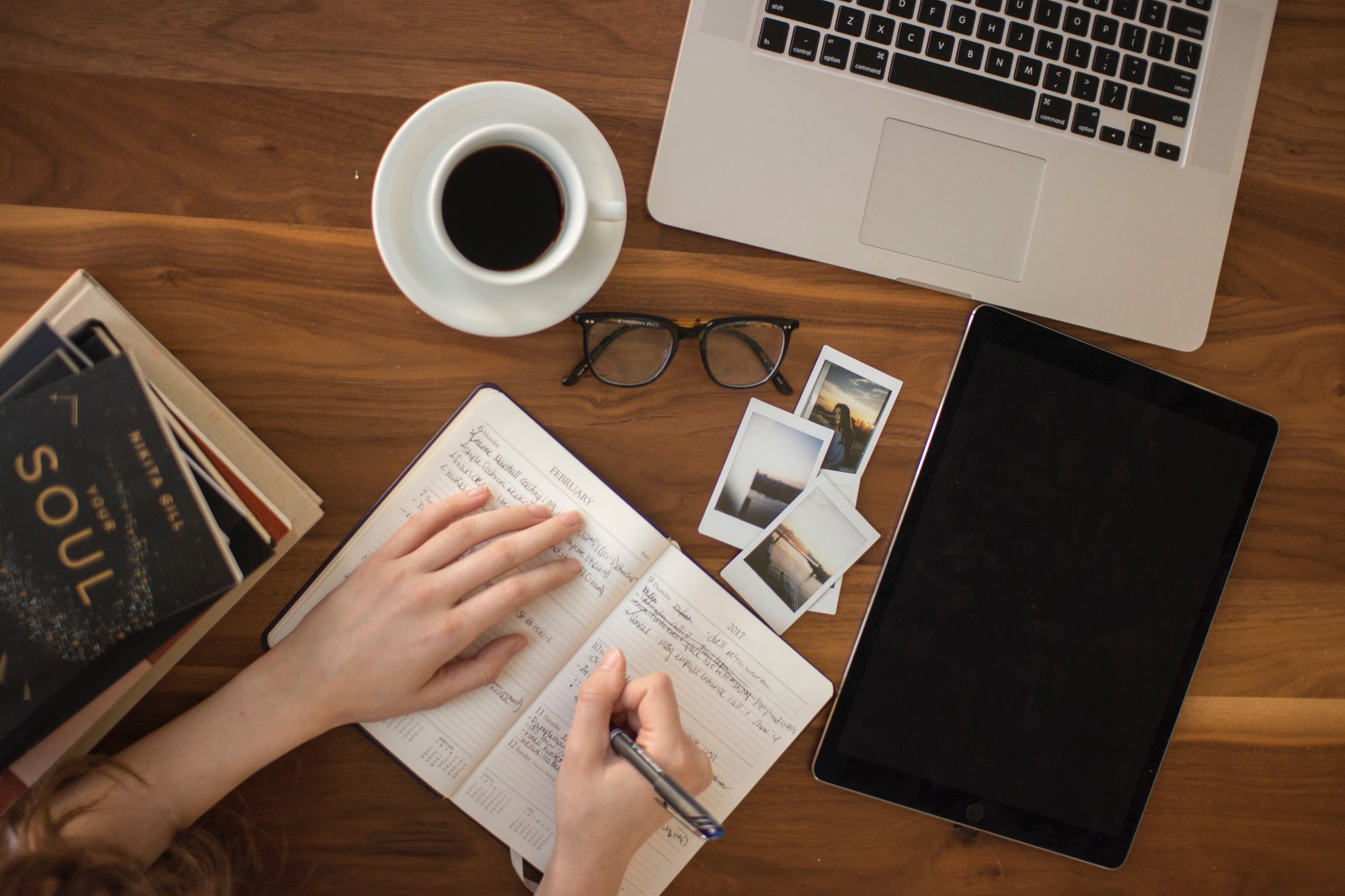Person journaling on table with laptop