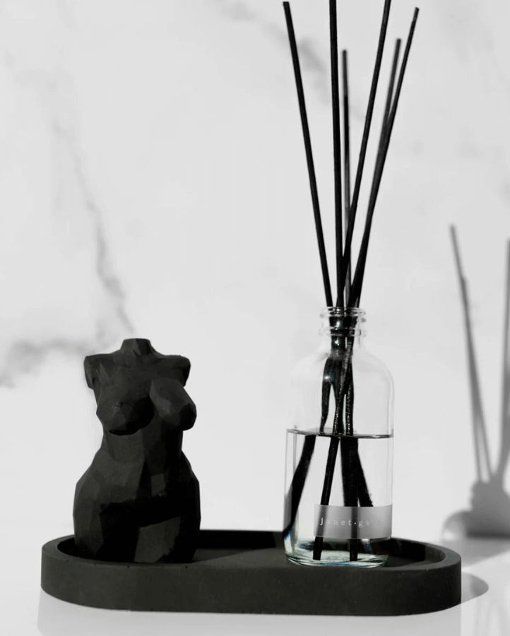 concrete statue and diffuser displayed on a tray