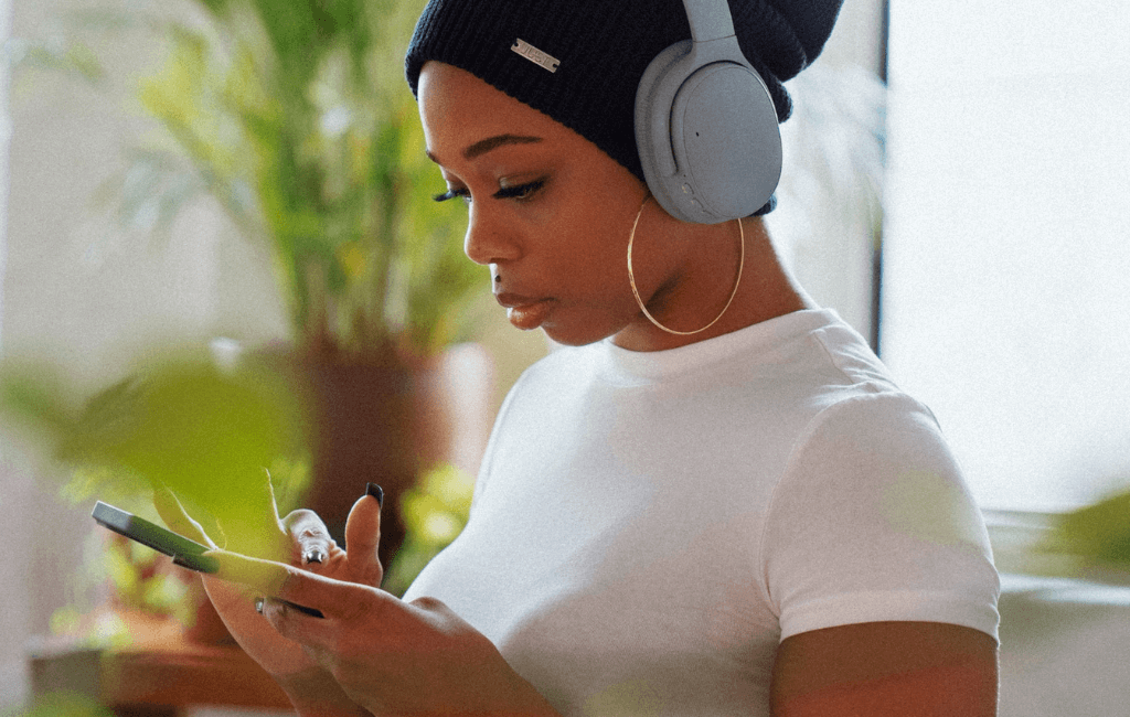 Young woman with headphones scrolling through trending audio on her phone for Instagram