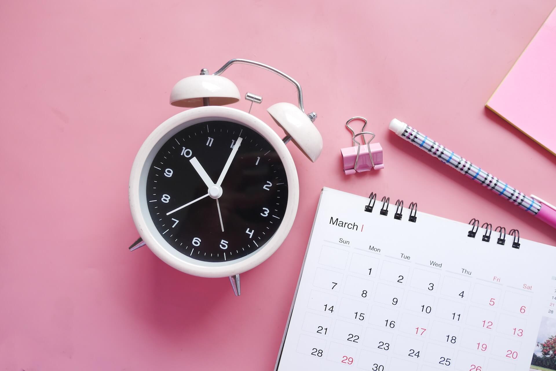create your own social media calendar in buffer: a calendar and a clock, laid out on a pink background