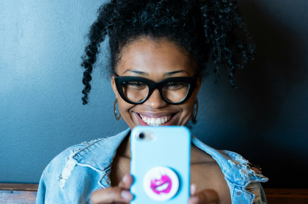 Woman filming with her phone while smiling to show Instagram reels trends