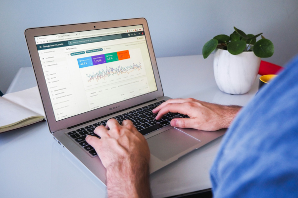 view of a man's hands typing on a macbook laptop with the screen showing graphs from a free seo tool