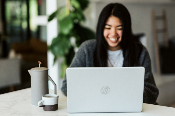 An image of a smiling woman working on a laptop to illustrate LinkedIn personal branding