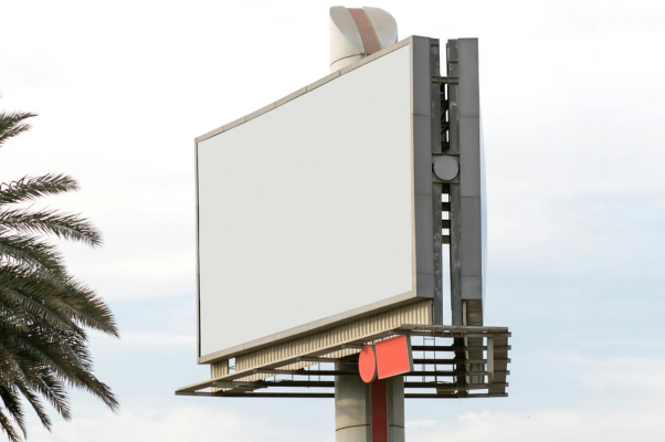 An empty billboard stands next to a palm tree to indicate social media advertising