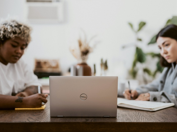 Two women take notes while viewing something on the same laptop to illustrate digital marketing tools