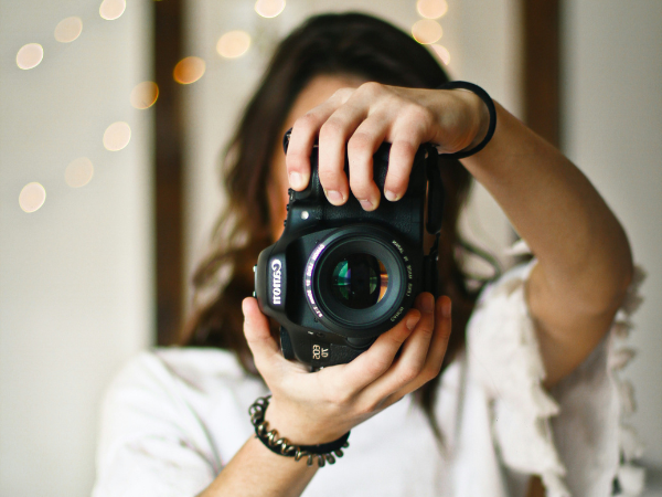 A woman taking a photo with a cannon DSLR camera, to illustrate taking the perfect facebook cover photo