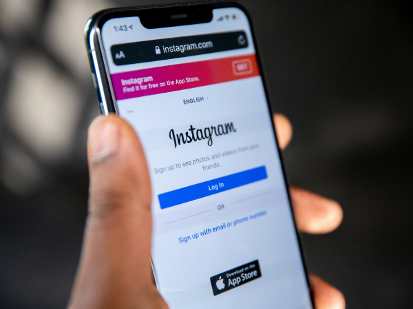 Man's hand holding a phone with the Instagram login on the screen, illustrating scheduling posts on Instagram