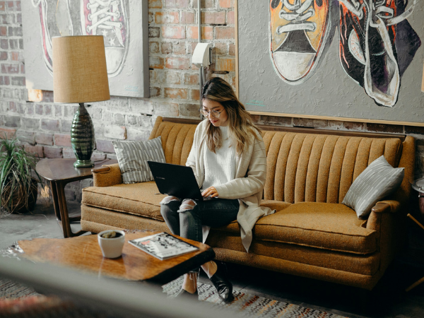 Woman uses a laptop in a trendy cafe to illustrate using AI marketing tools