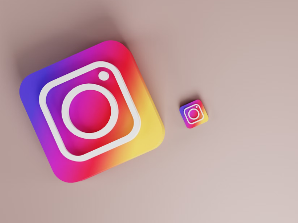 Two 3d stickers of the instagram logo, side by side on a beige surface