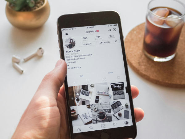 A hand holding a phone with Instagram open on the screen to illustrate using Instagram analytics tools