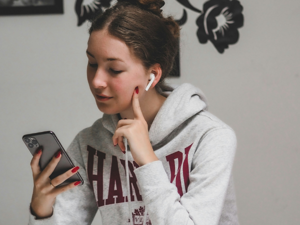 young woman in hoodie looks at her phone to illustrate finding the perfect instagram caption