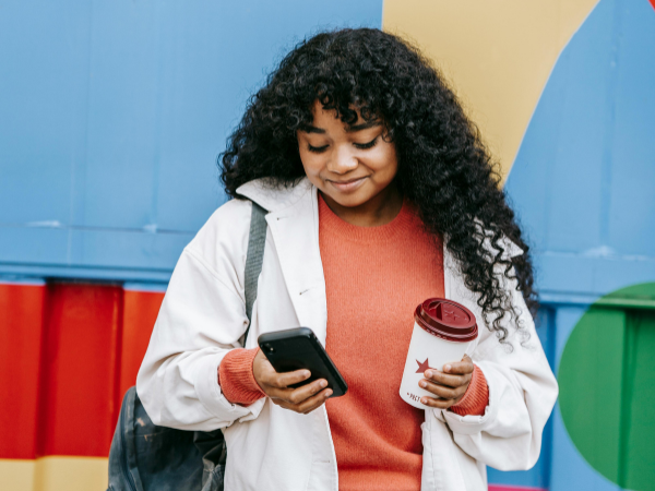 A woman smiles as she looks at her phone to illustrate resetting your Instagram algorithm