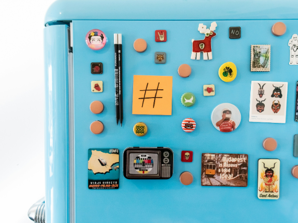 A blue refrigerator covered in magnets and a hashtag symbol on a post-it note, to illustrate hashtags on TikTok