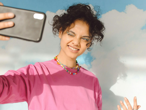 a young woman takes a selfie with her phone to illustrate creating user-generated content (UGC)
